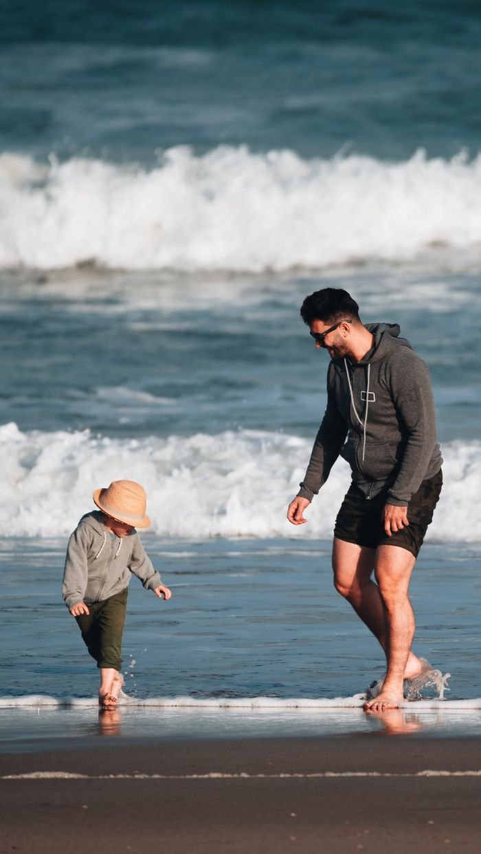 our-services-1 A father and child enjoying a playful walk on a sunny beach.