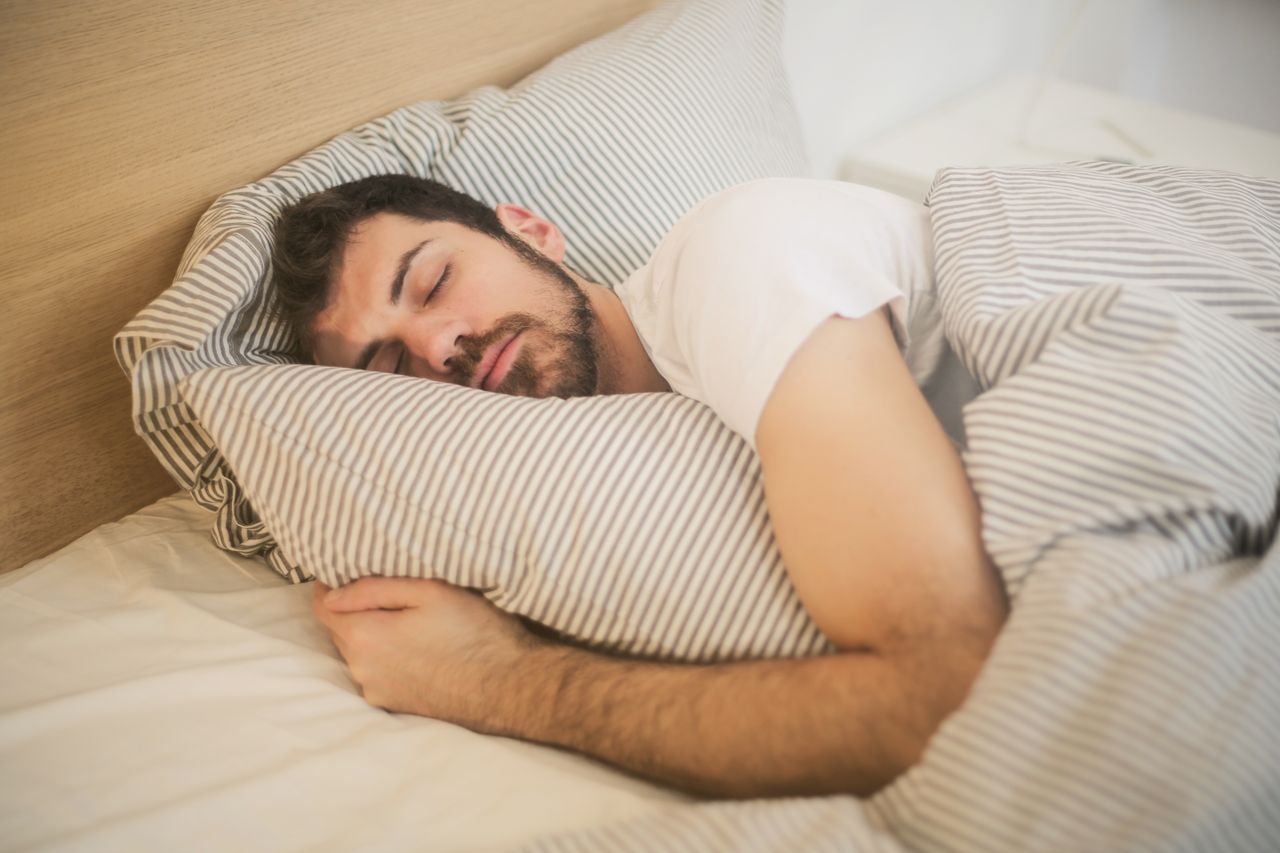 services-01 Man sleeping peacefully on striped bedding, embracing relaxation and comfort.