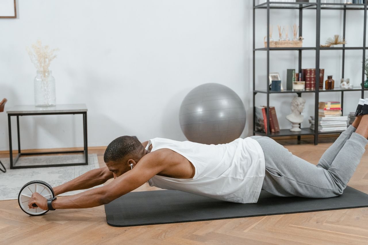 services-01 Man using an ab roller on a yoga mat indoors, promoting fitness and healthy lifestyle.